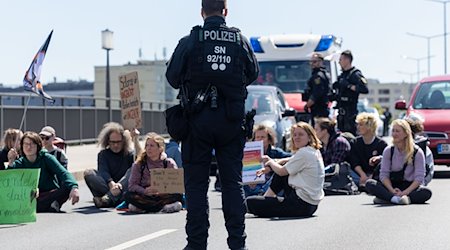 A police officer observes climate activists on the Carola Bridge in Dresden / Photo: Daniel Schäfer/dpa