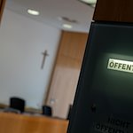 Eine Anzeigetafel weist an einem Sitzungssal auf eine öffentliche Verhandlung hin. / Foto: Stefan Puchner/dpa/Symbolbild