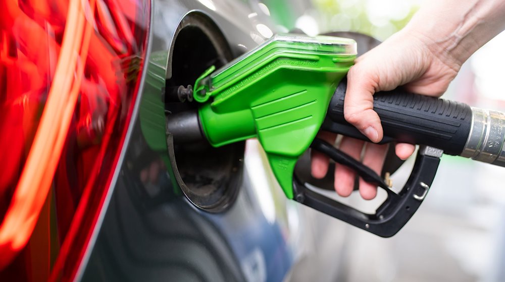 A woman holds a pump nozzle in her hand at a gas station and fills up a car / Photo: Sven Hoppe/dpa