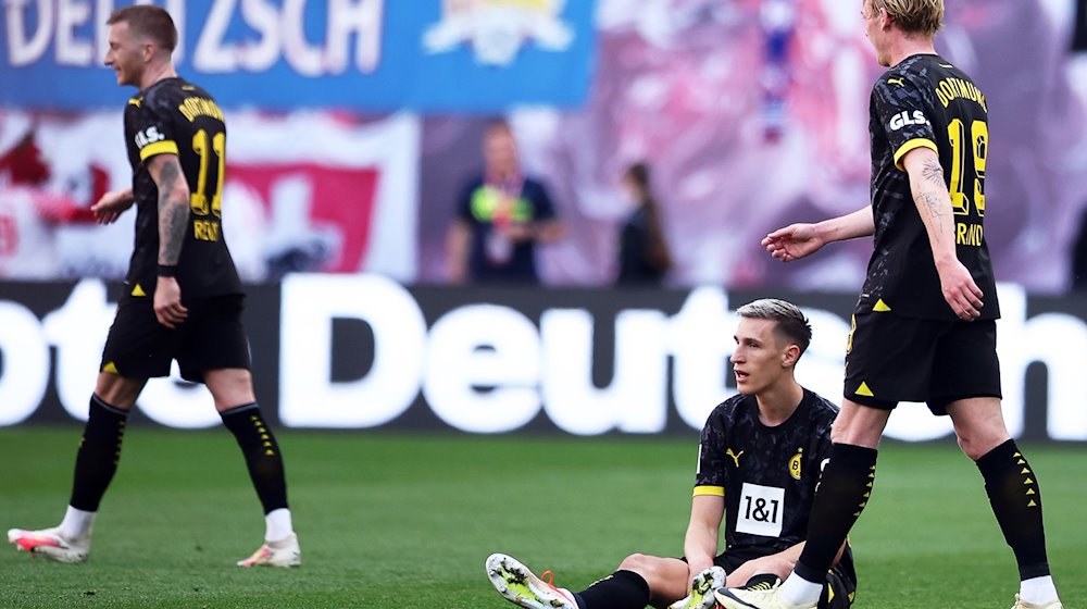 Dortmunds Nico Schlotterbeck (M) reagiert neben seinen Teamkollegen Marco Reus (l) und Julian Brandt. / Foto: Jan Woitas/dpa