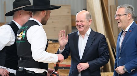 Federal Chancellor Olaf Scholz (SPD, 3rd from left) jokes with master carpenters Ralf Lepski (l), Felix Lepski (2nd from left) and Jörg Dittrich (r), President of the German Confederation of Skilled Crafts (ZDH) and President of the Dresden Chamber of Skilled Crafts, during his visit to a Dresden timber construction company / Photo: Robert Michael/dpa