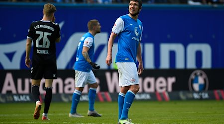 Damian Roßbach (d), del Rostock, mira el marcador durante una interrupción del juego. / Foto: Gregor Fischer/dpa