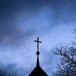 Dunkle Wolken ziehen über das Kreuz auf einer Kirche hinweg. / Foto: Julian Stratenschulte/dpa/Symbolbild
