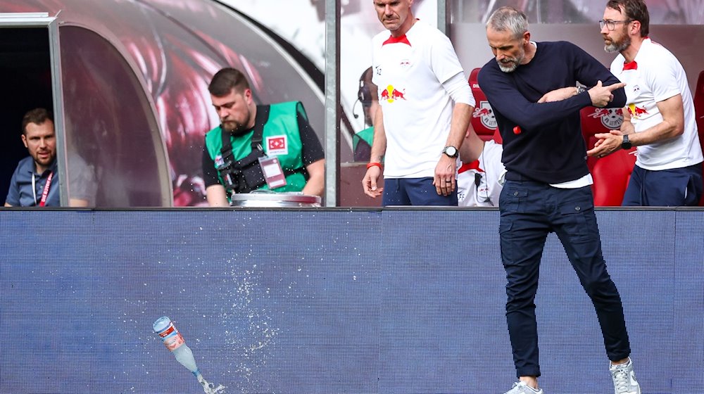 Leipzigs Trainer Marco Rose wirft mit dem Abpfiff eine Wasserflasche auf den Rasen. / Foto: Jan Woitas/dpa