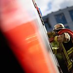 Eine Einsatzkraft der Feuerwehr nimmt während eines Pressetermins einen Schlauch aus einem Einsatzfahrzeug. / Foto: Marijan Murat/dpa