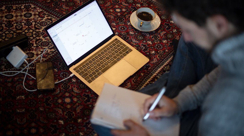 Ein Mann sitzt im Homeoffice mit Laptop auf dem Teppich und arbeitet. / Foto: Sina Schuldt/dpa/Illustration