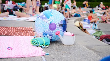 A beach ball and towels lie on the edge of a swimming pool / Photo: Annette Riedl/dpa/Symbolic image