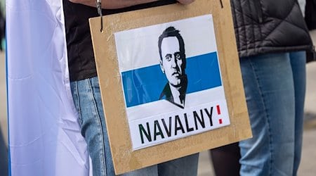 Ein Mann trägt ein Schild mit dem aufgedruckten Gesicht von dem gestorbenen Regimegegner Alexej Nawalny. / Foto: Thomas Banneyer/dpa/Archivbild