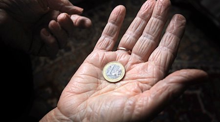 Eine Frau hält eine Euromünze. / Foto: Karl-Josef Hildenbrand/dpa