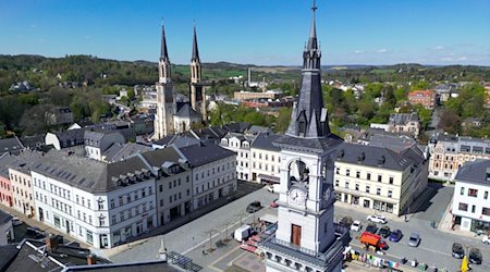 Die Doppeltürme der Stadtkirche St. Jakobi ragen hinter dem Marktplatz von Oelsnitz empor. / Foto: Hendrik Schmidt/dpa