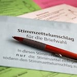 Stimmzettel und ein Umschlag für die Briefwahl liegen auf dem Tisch. / Foto: Oliver Berg/dpa/Symbolbild