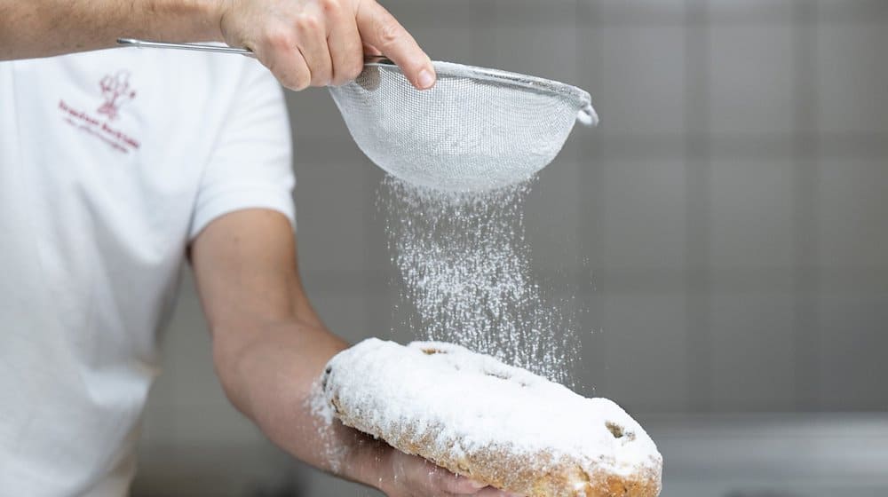 Tino Gierig, Bäckermeister, bestreut im Dresdner Backhaus einen Christstollen mit Puderzucker. / Foto: Sebastian Kahnert/dpa