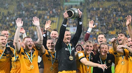 Dynamos Stefan Kutschke und die Mannschaft jubeln mit dem Pokal nach dem Sieg. / Foto: Robert Michael/dpa