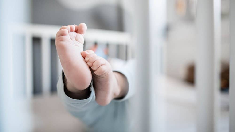 Die Füße eines Babys sind in einem Kinderbett zu sehen. / Foto: Fabian Strauch/dpa/Symbolbild