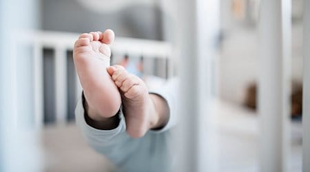 Die Füße eines Babys sind in einem Kinderbett zu sehen. / Foto: Fabian Strauch/dpa/Symbolbild