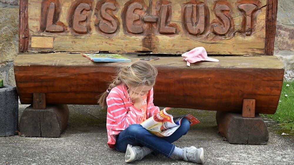 Дитина сидить за читанням перед лавкою "Lese-Lust" у школі в Мюґельні. Міністерство освіти і культури продовжує проект "Читацькі скаути", який реалізує Stiftung Lesen, ще на два роки (2024 і 2025) і надає йому фінансову підтримку у розмірі 50 000 євро. / Фото: Waltraud Grubitzsch/dpa-Zentralbild/dpa