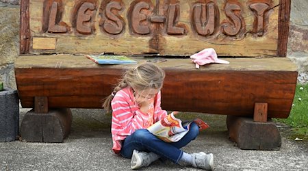 A child sits reading in front of the "Lese-Lust" bench at the school in Mügeln. The Ministry of Culture is extending the "Reading Scouts" project run by Stiftung Lesen for a further two years (2024 and 2025) and is supporting it financially with 50,000 euros. / Photo: Waltraud Grubitzsch/dpa-Zentralbild/dpa