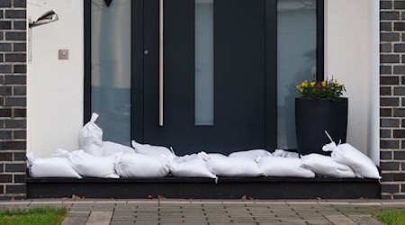 Sandsäcke liegen vor einer Haustür. / Foto: Friso Gentsch/dpa