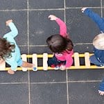 Kinder balancieren während eines Pressetermins auf dem Spielplatz einer Kindertagesstätte auf einem Brett. / Foto: Sebastian Kahnert/dpa