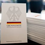 Das Grundgesetz der Bundesrepublik Deutschland liegt bei einer Einbürgerungszeremonie aus. / Foto: Julian Stratenschulte/dpa