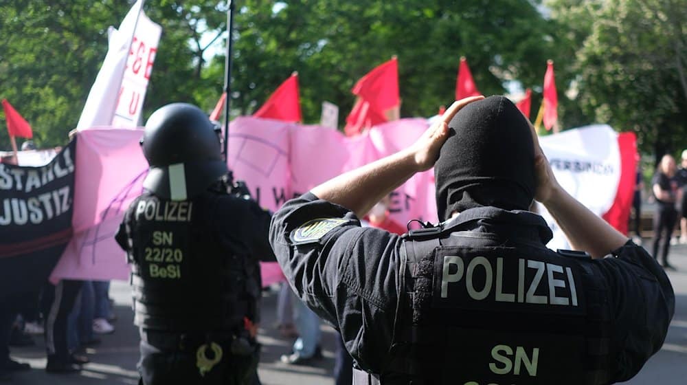 Polizisten setzen bei einer linken Demonstration Schutzhelme auf. / Foto: Sebastian Willnow/dpa