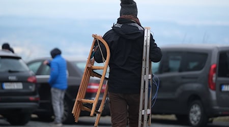 Un hombre transporta dos toboganes por un aparcamiento en el Fichtelberg, en los Montes Metálicos / Foto: Sebastian Willnow/dpa