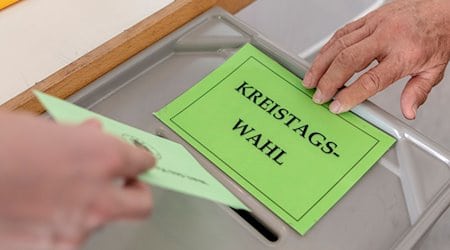 رجل يسلم ورقة اقتراعه لانتخابات مجلس المقاطعة في مكتب الاقتراع. / الصورة: باتريك زيغر/وكالة الصحافة الألمانية