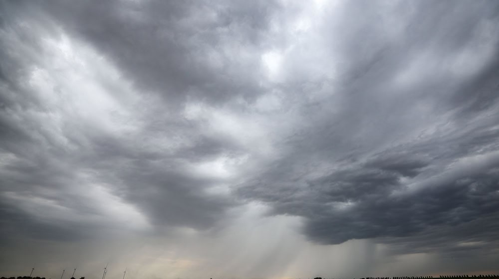 Eine Regenfront zieht über ein Getreidefeld hinweg. / Foto: Jan Woitas/dpa