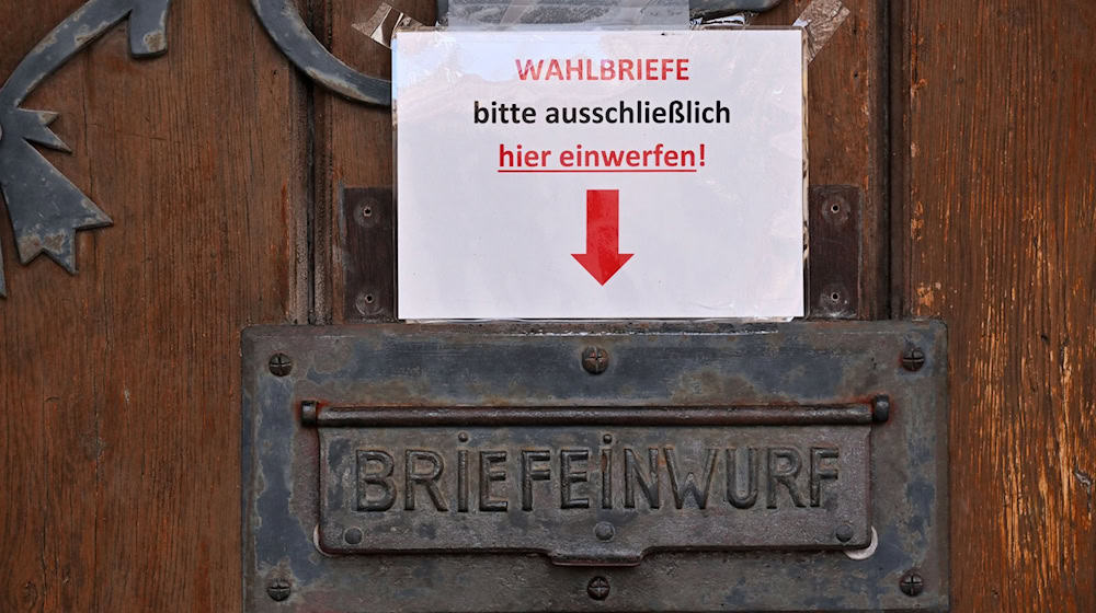 «Wahlbriefe bitte ausschließlich hier einwerfen!», steht auf dem Papier an einem Briefkasten. / Foto: Martin Schutt/dpa
