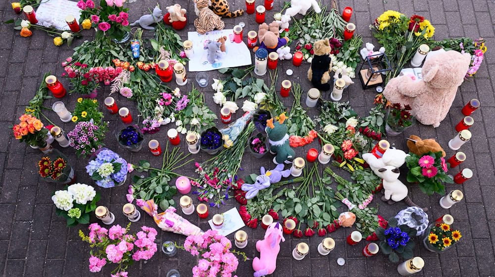 Menschen haben Blumen, Kerzen und Teddybären in der Nähe der Wohnung des getöteten Mädchens auf den Gehweg gelegt. / Foto: Robert Michael/dpa