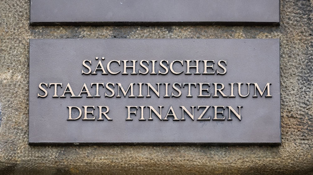 Ein Schild "Sächsisches Staatsministerium der Finanzen" ist am Eingang des Gebäudes angebracht. / Foto: Robert Michael/dpa