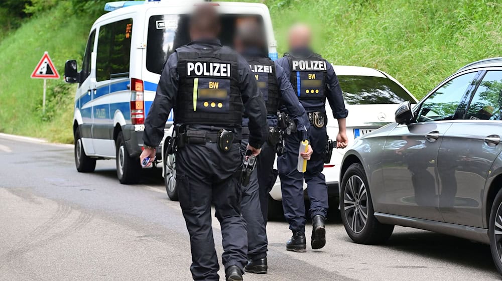 Einsatzkräfte der Polizei gehen an einer Straße vor einem Anwesen in einem Waldgebiet. Durchsucht wird ein Gebäudekomplex und ein Grundstück in Zusammenhang mit einer Razzia gegen mutmaßliche Unterstützer um eine Reichsbürger Gruppierung. / Foto: Bernd Weißbrod/dpa