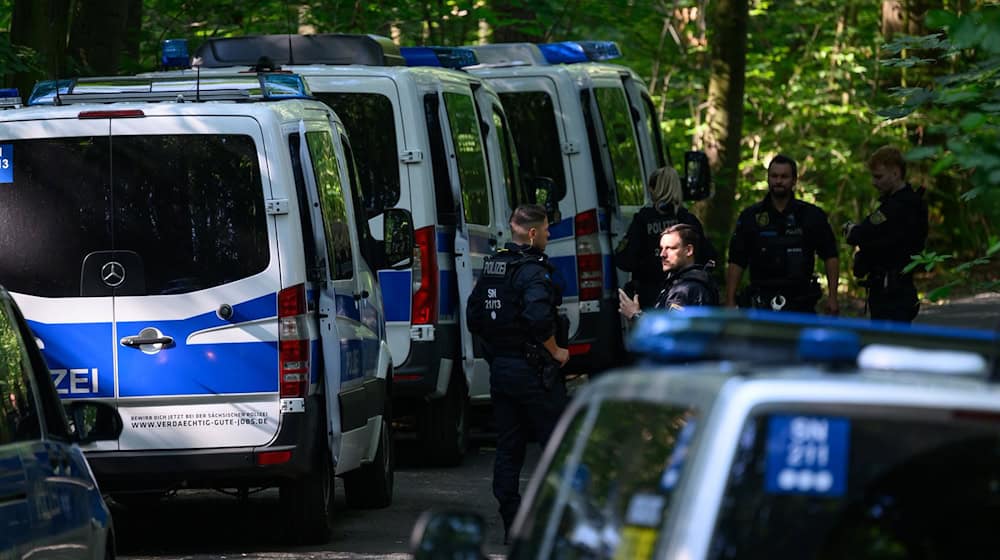 Polizisten stehen auf einer Straße in einem Wald. Bei der Suche nach der vermissten neunjährigen Valeriia hat die Polizei im sächsischen Döbeln eine Leiche gefunden. Die Polizei teilte mit, es werde geprüft, ob es sich dabei um das seit dem 3. Juni vermisste Mädchen handle. / Foto: Robert Michael/dpa