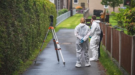 Polizeibeamte stehen an einem Tatort auf der Straße. In einem nahe gelegenen Haus war es zu einem Gewaltverbrechen mit drei Toten gekommen. / Foto: David Breidert/dbgrafie.de/dpa