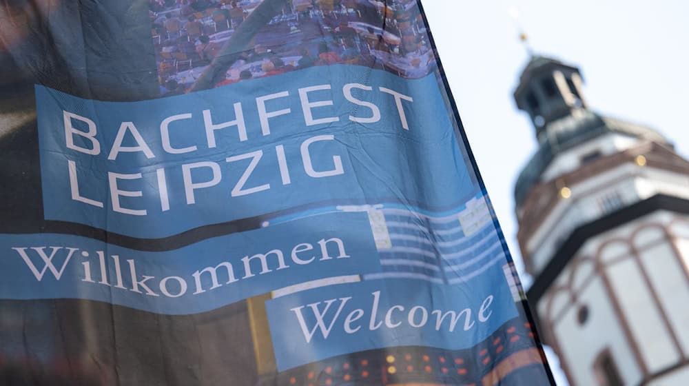 A flag of the Leipzig Bach Festival flies next to the tower of St. Thomas Church / Photo: Hendrik Schmidt/dpa