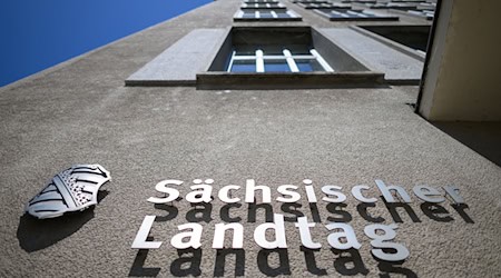 Sächsischer Landtag und eine Wappen von Sachsen sind an der Fassade am Altbau des Parlamentsgebäudes montiert. / Foto: Robert Michael/dpa