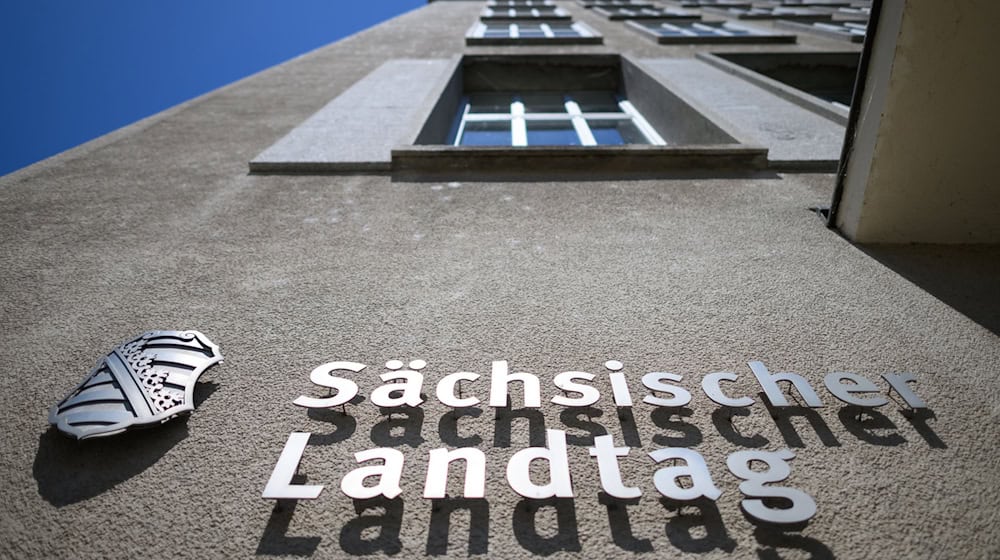 Sächsischer Landtag und eine Wappen von Sachsen sind an der Fassade am Altbau des Parlamentsgebäudes montiert. / Foto: Robert Michael/dpa