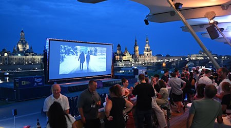 Los invitados a las Noches de Cine del año pasado observan una pantalla con el casco antiguo de Dresde como telón de fondo. / Foto: Robert Michael/dpa/Archivbild
