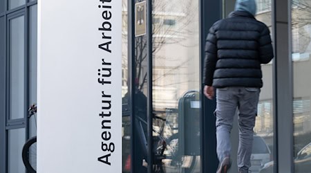 Ein Mann geht hinter einer Stele mit der Aufschrift „Agentur für Arbeit“. In Sachsen sind 10.100 Lehrstellen unbesetzt. / Foto: Sebastian Kahnert/dpa