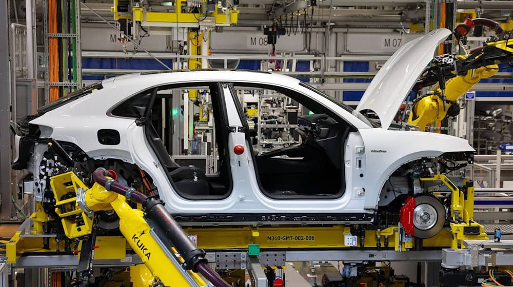 Industrieroboter arbeiten an einem vollelektrischen Porsche Macan nach der Hochzeit (der Verbindung von Fahrwerk und Motor mit der Karosse) im Werk Leipzig. / Foto: Jan Woitas/dpa