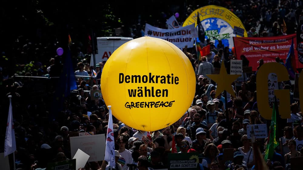 Los participantes sostienen un globo amarillo de Greepeace con el texto "Vota por la democracia" durante una manifestación en la Columna de la Victoria la víspera de las elecciones europeas contra el extremismo de derechas y a favor de una sociedad democrática, abierta y diversa / Foto: Carsten Koall/dpa