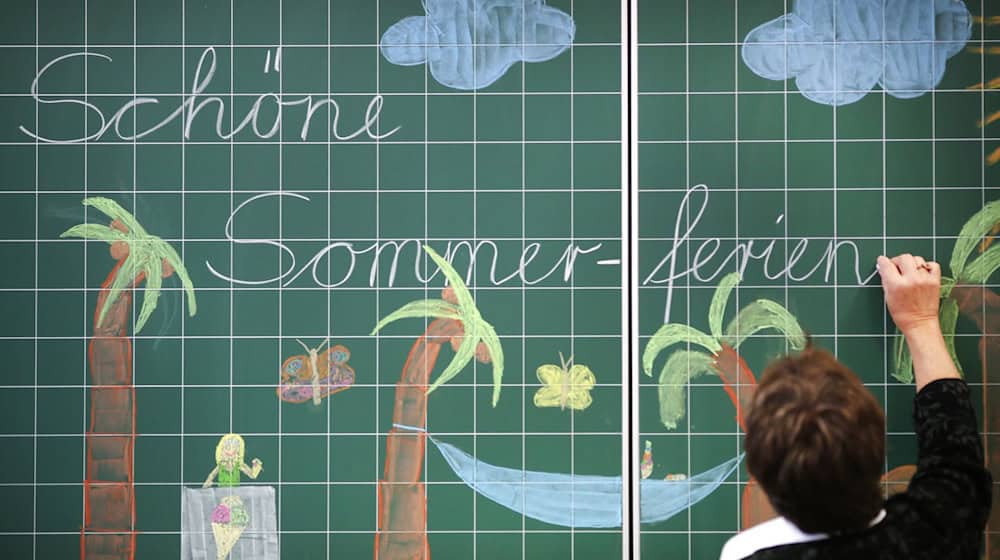 A teacher writes "Have a nice summer vacation" on a blackboard in an elementary school / Photo: picture alliance/dpa/Illustration