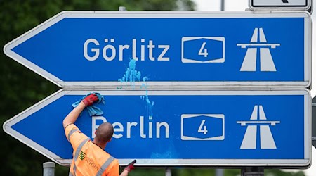 رجل ينظف لافتة زرقاء وبيضاء لمخرج الطريق السريع A4 باتجاه برلين وغورليتس. / صورة: سيباستيان كانيرت/dpa-زينترالبيلد/dpa