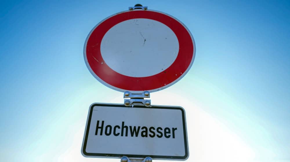Ein Verkehrsschild für «Durchfahrt verboten» mit dem Zusatz «Hochwasser» steht am Ufer eines Flusses. / Foto: Soeren Stache/dpa/Symbolbild