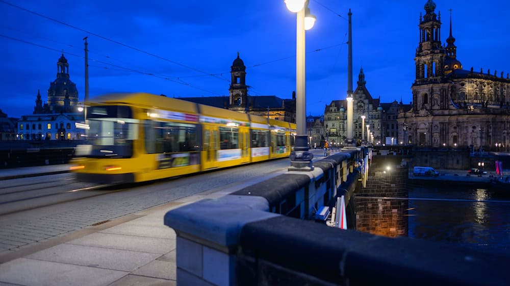Eine Straßenbahn der Dresdner Verkehrsbetriebe (DVB) fährt am Abend über die Augustusbrücke in die Altstadt. / Foto: Robert Michael/dpa