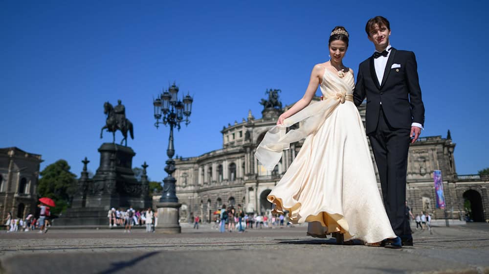 Los modelos Franziska Rose y Max Jeschke presentan el vestido y el traje para el baile de los debutantes delante de la Semperoper en la Plaza del Teatro. / Foto: Robert Michael/dpa