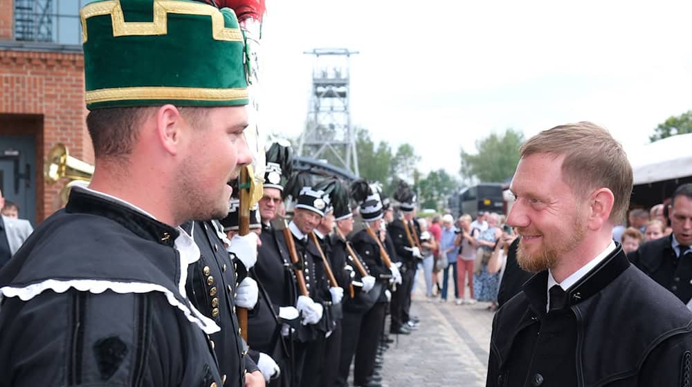 Minister President Michael Kretschmer (CDU) is welcomed by miners in front of the Oelsnitz Coal World Museum for the ceremony. / Photo: Sebastian Willnow/dpa