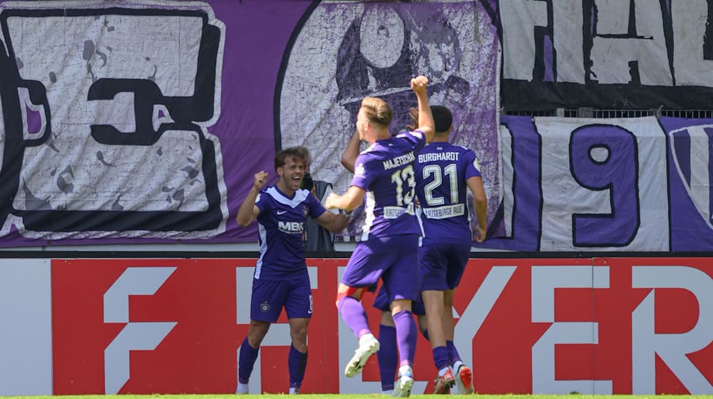 Mika Clausen (i), del Aue, celebra con Erik Majetschak (centro) y Maxim Burghard su gol del 1-0 / Foto: Robert Michael/dpa