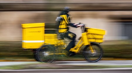 Ein Postbote ist in Dresden unterwegs (Symbolbild). / Foto: Robert Michael/dpa