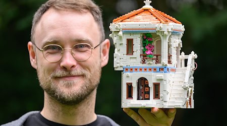 Martin Gebert, Lego-Baumeister aus Dresden, hält eine Villa aus Legosteinen in der Hand, die als Teil seines Weinbergs im Lego House im dänischen Billund zu sehen sein wird. / Foto: Robert Michael/dpa